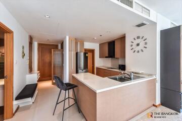 Modern kitchen area with sleek countertops, bar seating, and a clock on the wall