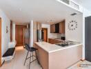 Modern kitchen area with sleek countertops, bar seating, and a clock on the wall