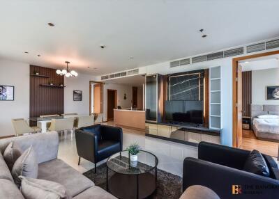 Living room with modern decor, featuring a dining area, a TV, and a glimpse of the bedroom.