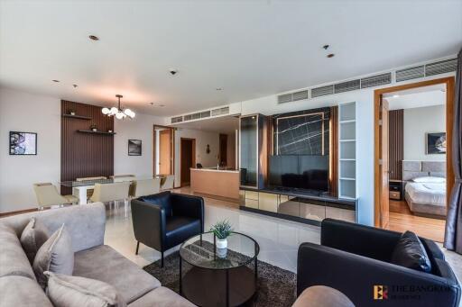 Living room with modern decor, featuring a dining area, a TV, and a glimpse of the bedroom.