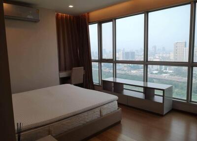 Spacious bedroom with large windows and a city view