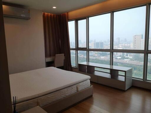 Spacious bedroom with large windows and a city view