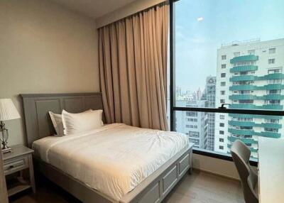 Bed positioned near a window with a city view