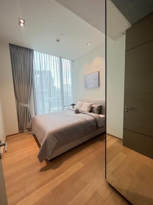 Modern bedroom with wooden flooring and large window