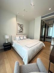 Modern bedroom with a large bed, artwork, and wooden flooring