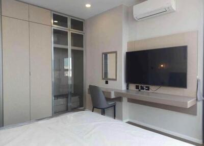 Modern bedroom with built-in wardrobe, desk, and wall-mounted TV