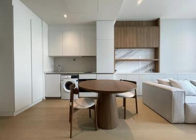 Modern kitchen and living area with dining table, built-in appliances, and open shelving