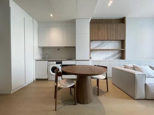 Modern kitchen and living area with dining table, built-in appliances, and open shelving