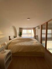 Cozy bedroom with a large bed, nightstand, and natural light through large windows