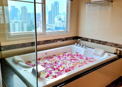 Luxury bathroom with city view, jacuzzi, and flower petals in the tub