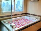 Luxury bathroom with city view, jacuzzi, and flower petals in the tub