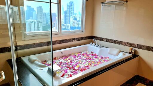 Luxury bathroom with city view, jacuzzi, and flower petals in the tub