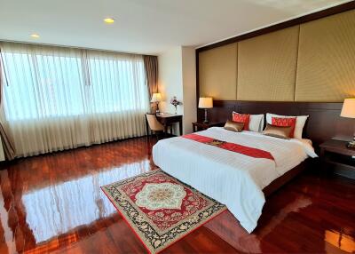 Spacious bedroom with wooden floors and large window