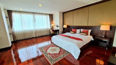 Spacious bedroom with wooden floors and large window