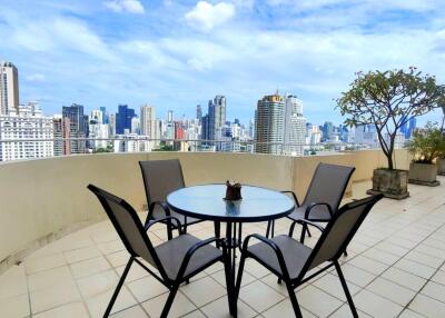 View of city skyline from a spacious balcony with a round glass table and four chairs