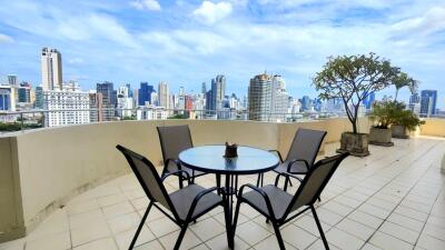 View of city skyline from a spacious balcony with a round glass table and four chairs