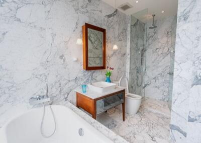 Modern bathroom with marble walls, bathtub, shower, and vanity