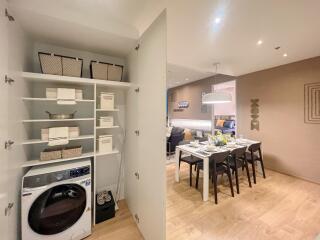 Laundry area with washer and storage next to a dining area