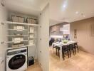 Laundry area with washer and storage next to a dining area