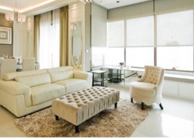 Modern living room with neutral color tones, featuring a plush sofa, armchair, and a tufted ottoman.