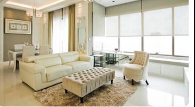 Modern living room with neutral color tones, featuring a plush sofa, armchair, and a tufted ottoman.