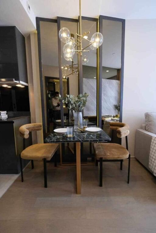 Modern dining area with two chairs, a small table, and contemporary lighting