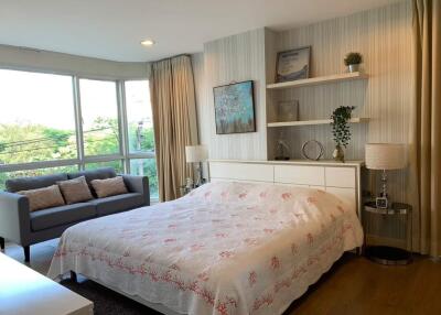 Spacious bedroom with large windows, double bed, and sitting area