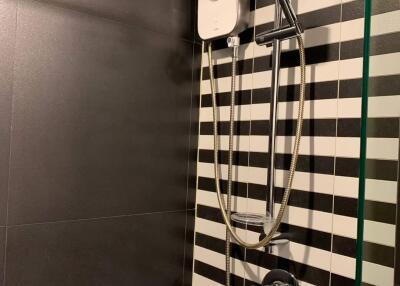 Modern bathroom with black and white striped tiles and a shower unit