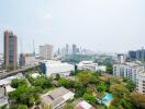 View of cityscape from above with various buildings, trees, and construction cranes