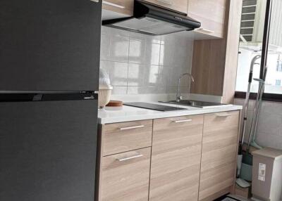 Modern kitchen with wooden cabinets, black refrigerator, and tiled backsplash