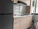 Modern kitchen with wooden cabinets, black refrigerator, and tiled backsplash