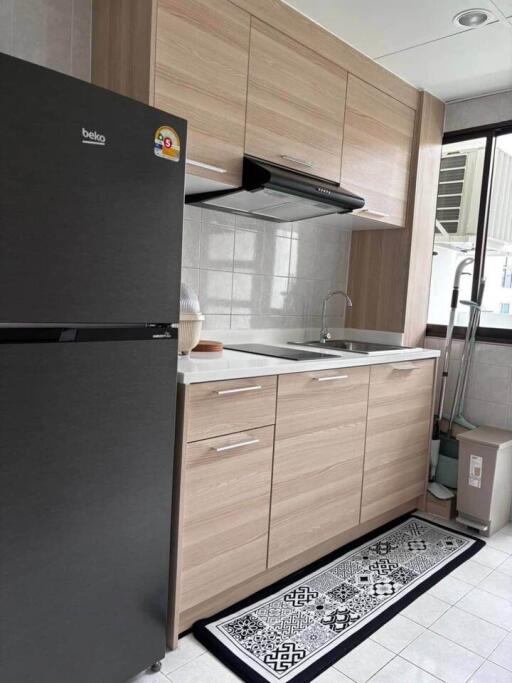 Modern kitchen with wooden cabinets, black refrigerator, and tiled backsplash