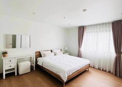 Spacious and well-lit bedroom with a large bed and wooden floor