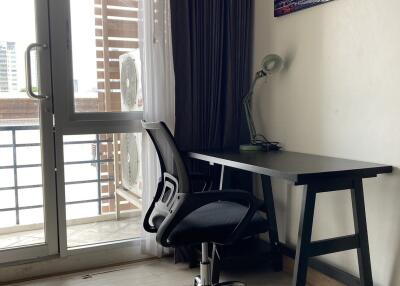 Workspace with desk, chair, lamp, and artwork near balcony