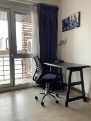 Workspace with desk, chair, lamp, and artwork near balcony