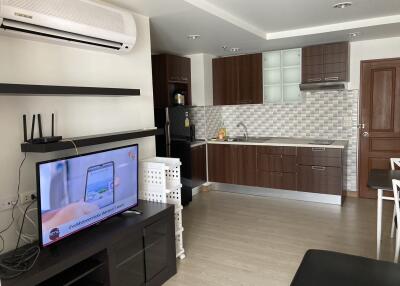 Modern kitchen with wooden cabinets, TV, and dining area