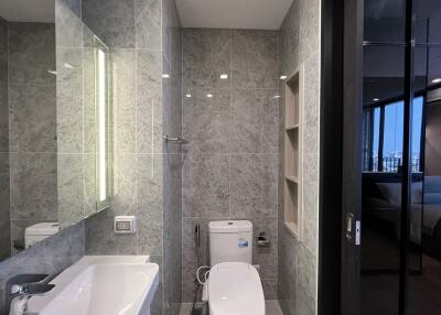 Modern bathroom with grey tiled walls and backlit mirror