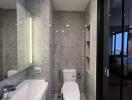 Modern bathroom with grey tiled walls and backlit mirror