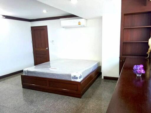 Spacious bedroom with wooden furniture and built-in shelving