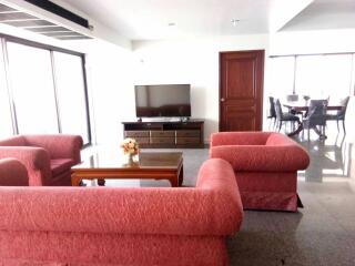 Spacious living room with red sofas and a TV