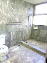 Modern gray-tiled bathroom with open shower and toilet