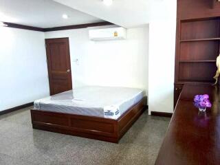 Spacious bedroom with a bed, wooden furniture, and an air conditioner