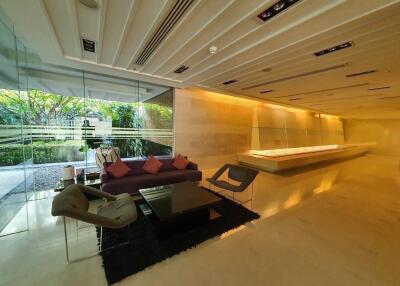 Modern living area with large glass walls, contemporary furniture, and recessed lighting