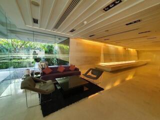 Modern living area with large glass walls, contemporary furniture, and recessed lighting