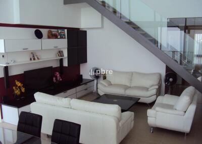 Modern living room with white sofas and a glass staircase