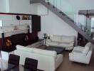 Modern living room with white sofas and a glass staircase