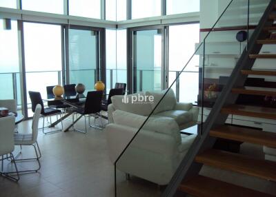 Modern living room with large windows, dining area, and staircase