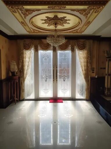 Elegant living room with ornate ceiling, chandelier, large decorative glass doors, and luxurious curtains